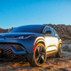 A photo of a blue Fisker Ocean electric SUV taken at sunset.